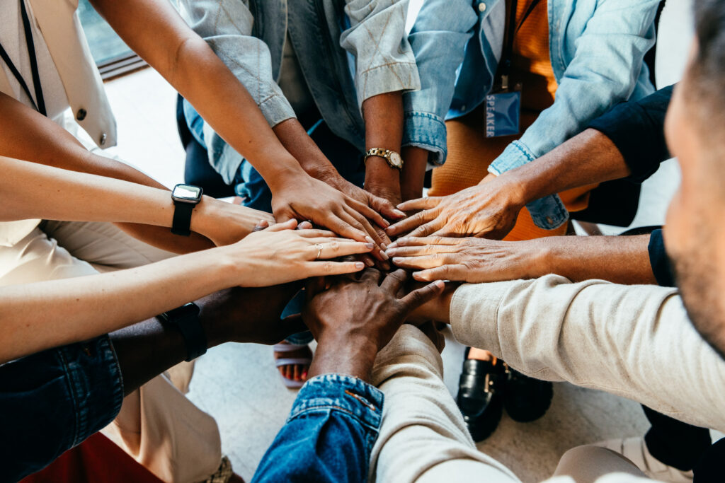 A group places their hands together in a circle to represent teamwork.