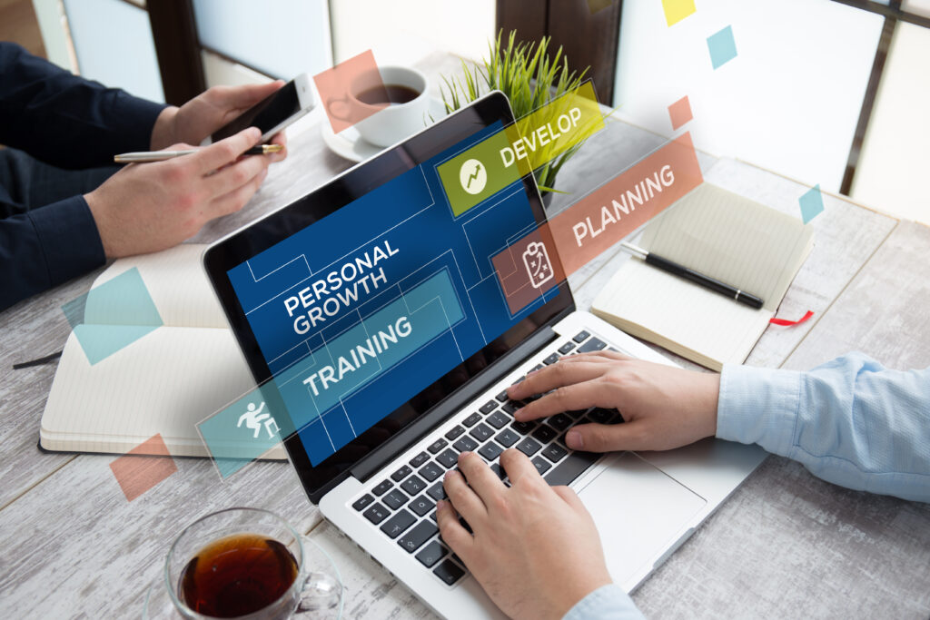 Personal growth and professional development concept showing people using a laptop and smartphone, with training, planning, and development graphics displayed on the screen.